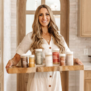 A woman holds a tray of seasoning containers.